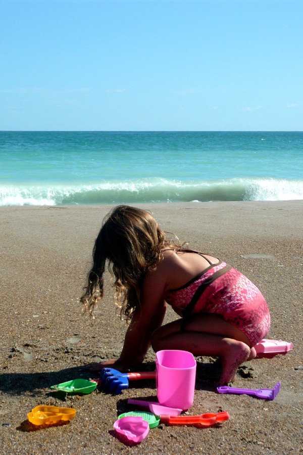 Girl playing in sand on beautiful beaches in Emerald Isle