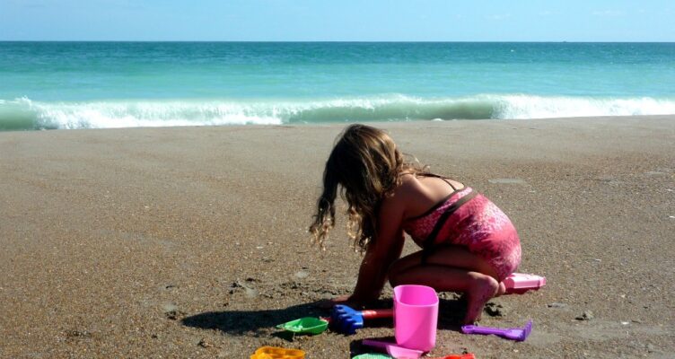 Girl playing in sand on beautiful beaches in Emerald Isle