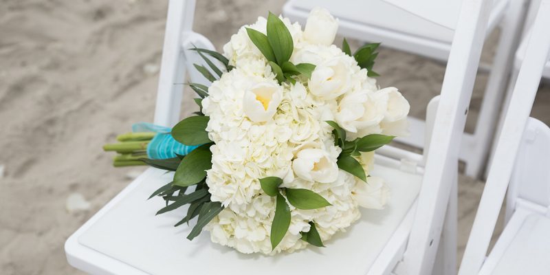 Beach wedding setup white flowers on white chair in emerald isle nc